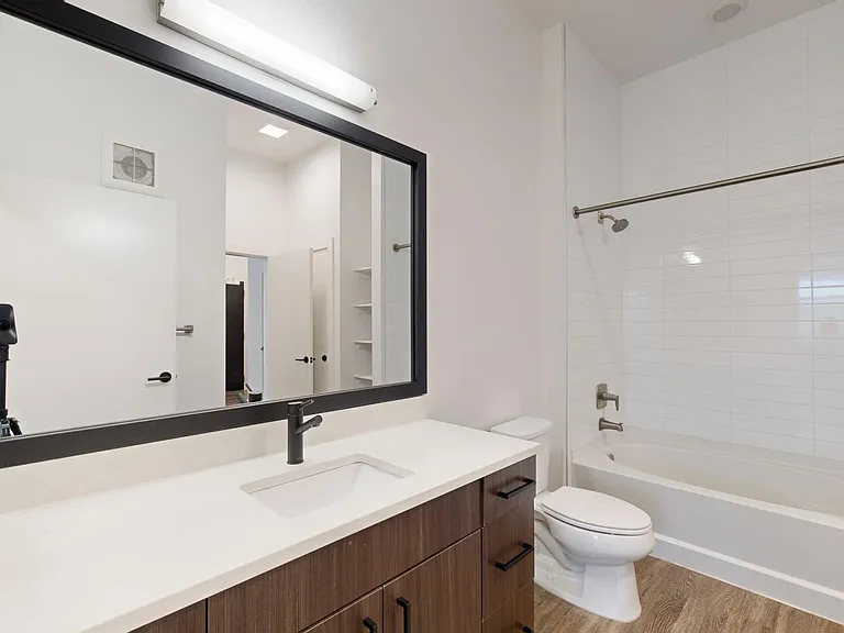 Apartment bathroom with large soaking tub and wood-style flooring.