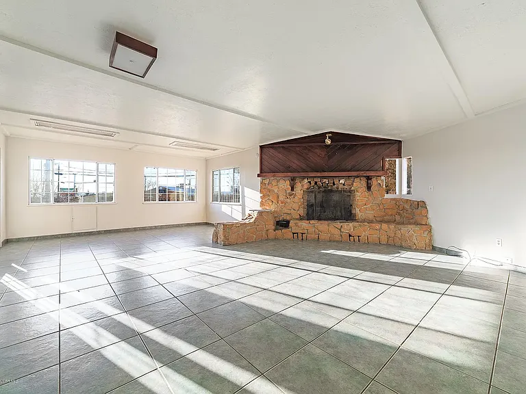 The entertainment room features a beautiful fireplace, creating the perfect setting for cozy evenings, while large, open windows overlook the beautifully landscaped backyard, filling the space with abundant natural light and beautiful views.