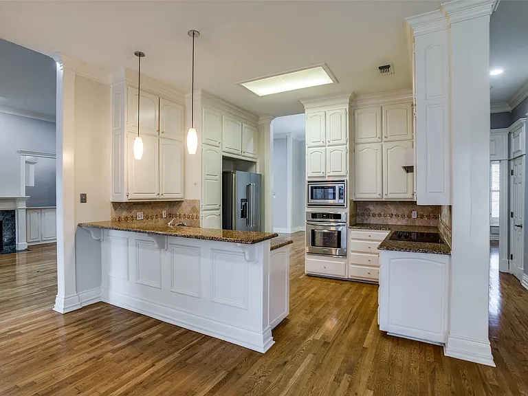The kitchen has a breakfast bar, granite countertops, decorative backsplash, stainless steel appliances, abundant cabinetry, and ornamental wood molding