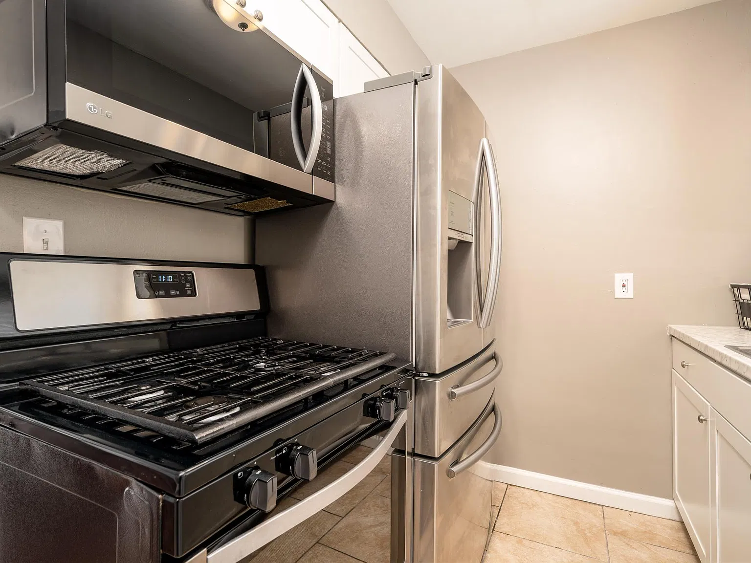 Stainless steel appliances, gas oven/stove, over-the-range microwave, and countertop depth fridge/freezer