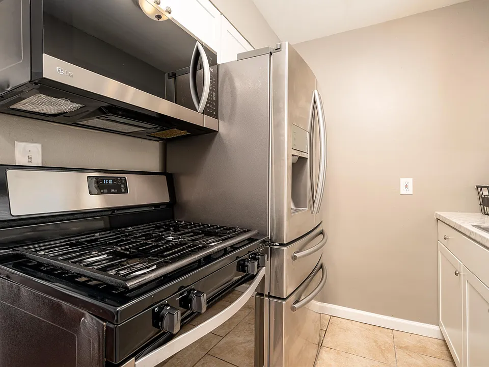Stainless steel appliances, gas oven/stove, over-the-range microwave, and countertop depth fridge/freezer