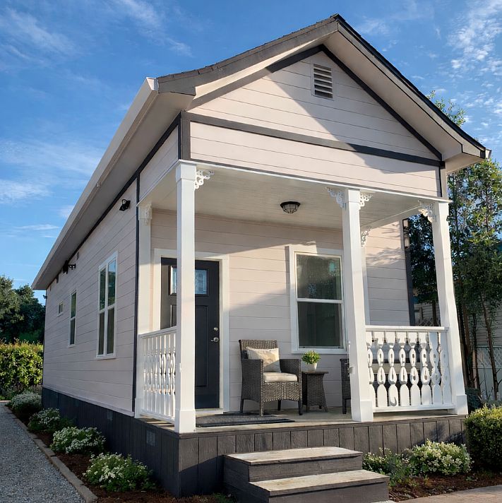 Detached cottage with a private covered porch, seating area, and charming Queen Anne Victorian architectural details that complement the adjacent historic main residence on the property.