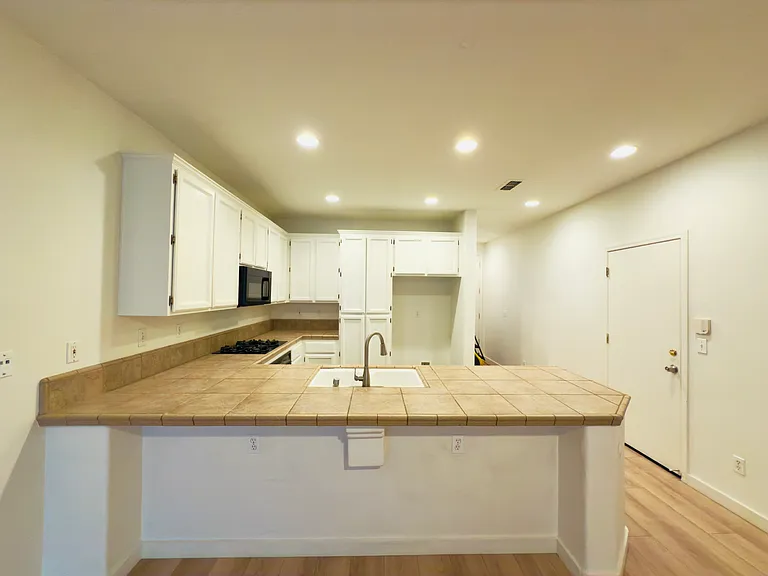 The kitchen boasts a sleek U-shaped modern design, high ceilings, and the perfect layout for cooking and entertaining!