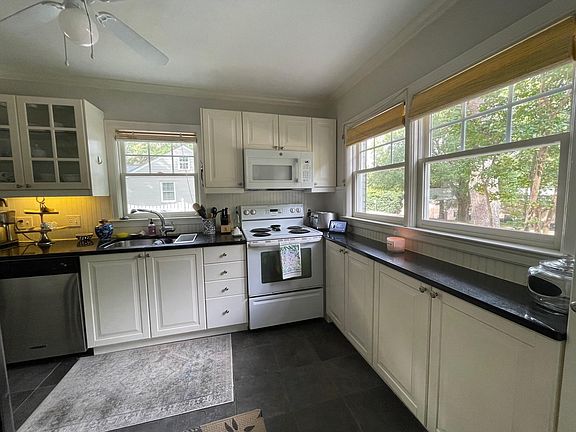 Kitchen with granite countertops, under counter lights, stove, microwave, dishwasher and refrigerator.