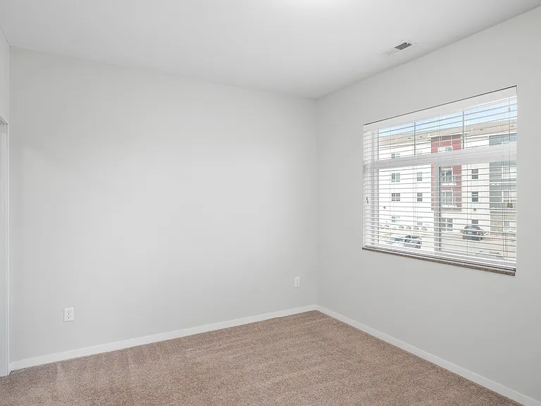 Bright and spacious bedroom with large window, fresh neutral walls, and plush carpet flooring, offering a cozy and inviting ambiance. Bright and spacious bedroom with large window, fresh neutral walls, and plush carpet flooring, offering a cozy and inviti