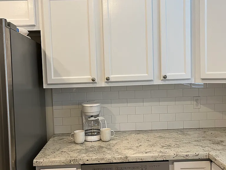 Downstairs kitchen: stainless steel appliances, granite countertops, white tile backsplash, and gray laminate flooring