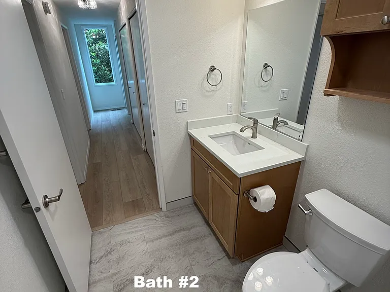 Lower level bathroom looking down the hallway towards the stairway features several closets for storage and in-home laundry access.