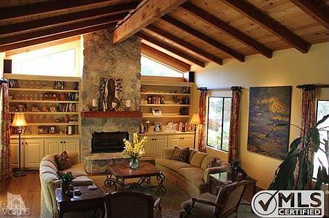 Spacious living room with stone-faced fireplace, hickory hardwood floors, handcrafted built-in bookc