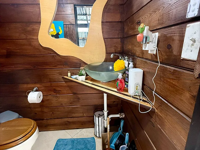 Rustic half bath with wood plank walls, vessel sink vanity, and wall mirrorconvenient for guests and daily use.