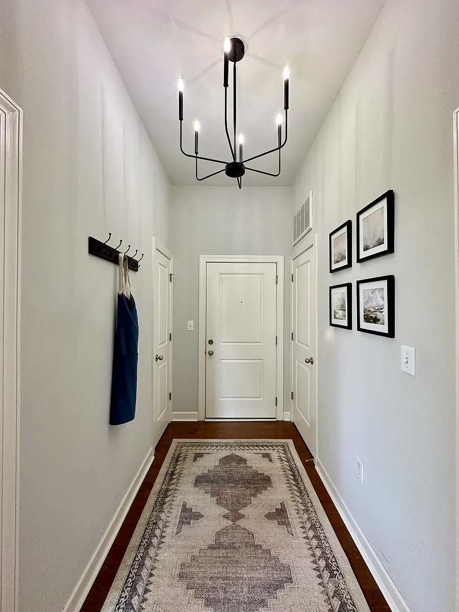 A welcoming entryway featuring high ceilings and a modern chandelier, creating a bright and airy feel. - 1903 Kenilworth Ave #306A