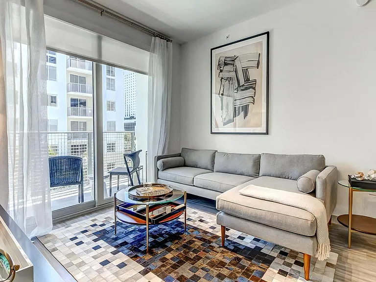 Indoor Living Area With Wall Art, Glass Coffee Table, and Access to Balcony
