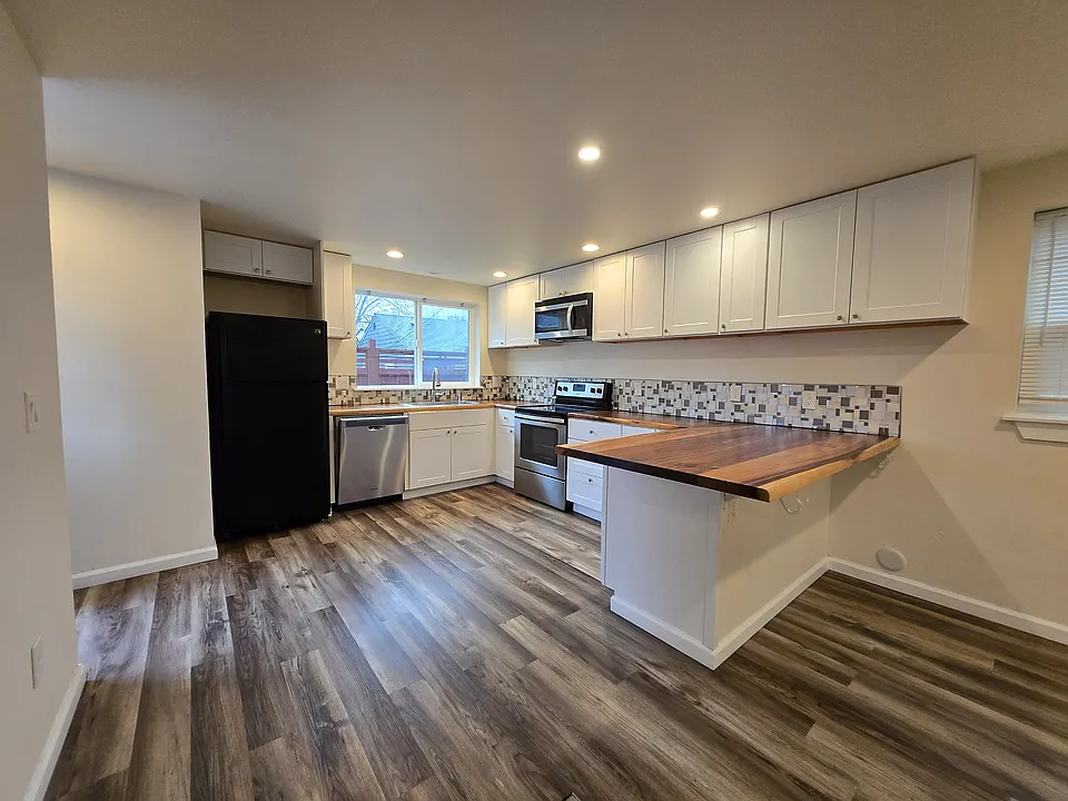 So many cabinets in this kitchen! Lux wood countertops and tile backsplash.