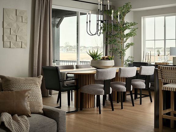A cozy and modern dining room with a large window, a wooden table surrounded by upholstered chairs,