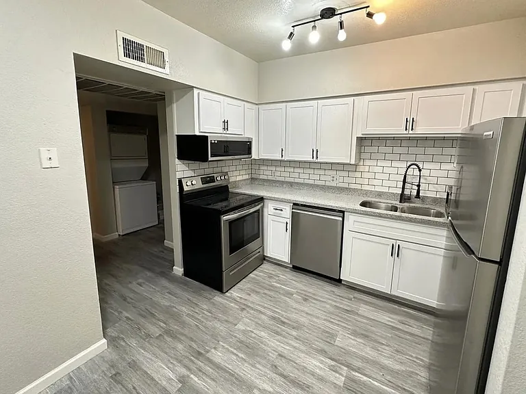 Updated kitchen with white cabinetry, subway-tile backsplash, and stainless steel appliances plus ample counter space.