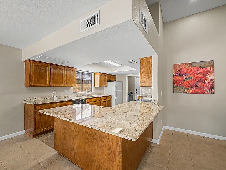 Spacious kitchen with granite counters, ample wood cabinetry, and a large peninsula for meal prep and casual seating.