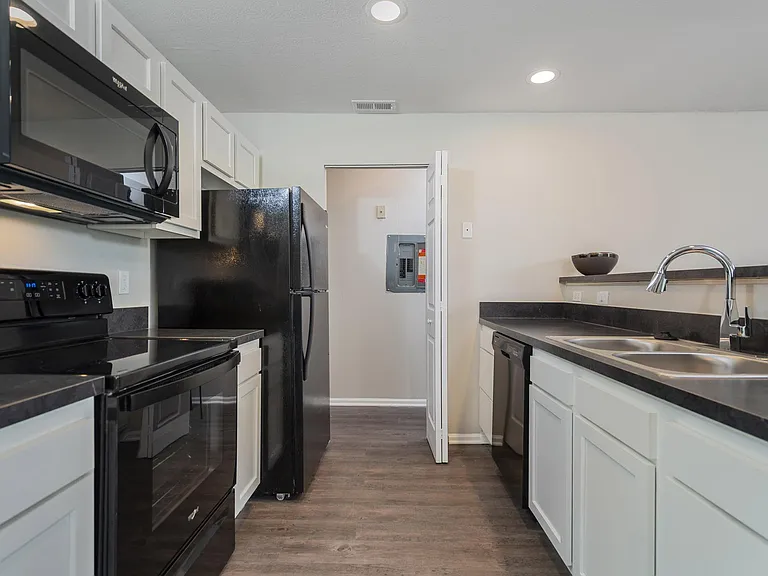 The Glenmount's modern kitchen with white shaker cabinetry, black countertops, and sleek black appliances.