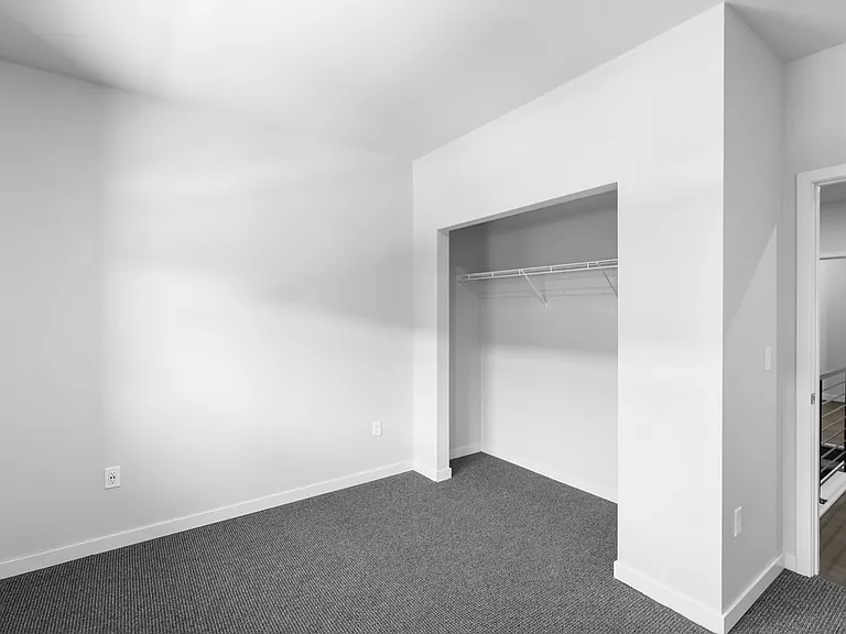 Bright, minimalist room with cozy carpet, open closet space, and modern railing in view. Bright, minimalist room with cozy carpet, open closet space, and modern railing in view.