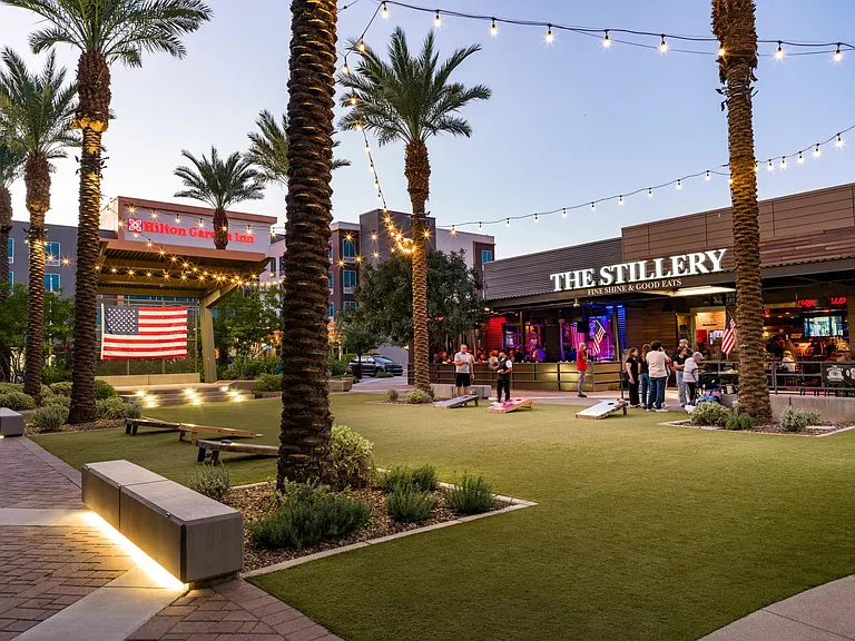 A nearby entertainment plaza in Chandler with outdoor dining, lawn games, and string lights, offering a lively evening scene close to Modera Chandler.