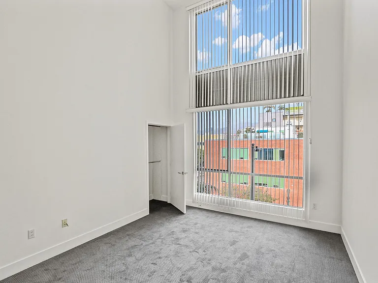 Spacious Bedroom with High Ceilings and Window Views