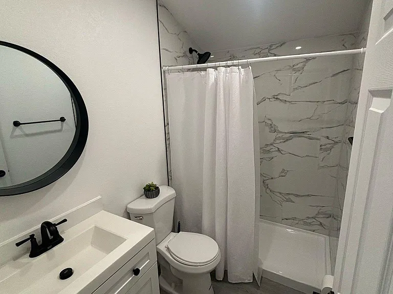 Impeccable bathroom with shower, toilet, mirror, towel set, and towel racks.