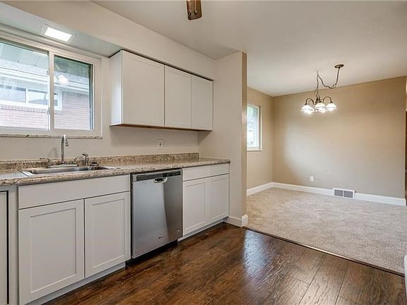 View of the new kitchen and dining area. White shaker cabinetry and stainless steel dishwasher.