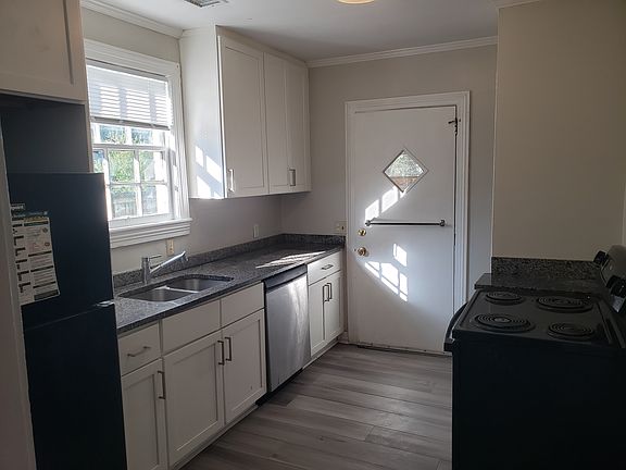 Kitchen. Fridge, dishwasher, and stove/oven are visible. White shaker cabinets are fairly new, as is granite countertop.