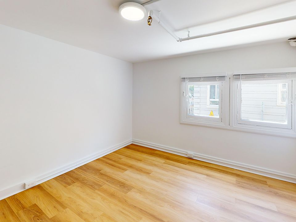 Sunlit room with a large window and wood-like flooring