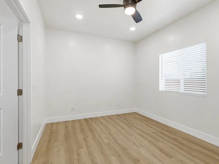 Natural lighting from bedroom window, recessed lighting, and ceiling fan.