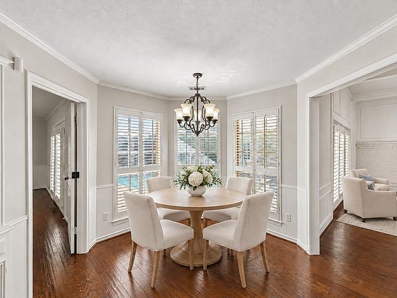 Eat-in kitchen breakfast area with built-in hutch, beautiful hardwoods, and overlooking pool. This photo is virtually staged.