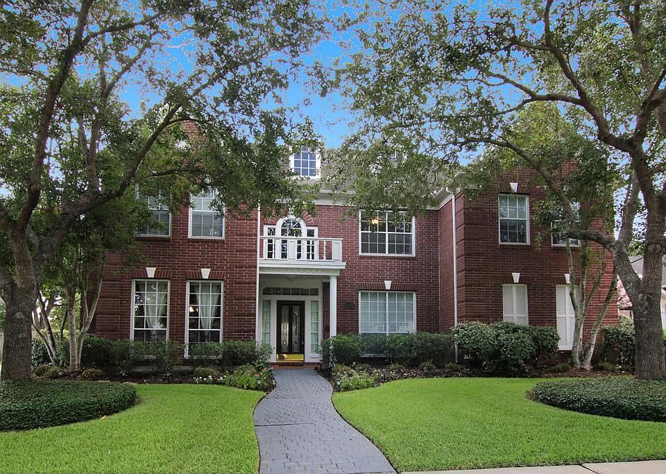 Traditional home (Newmark) with mature landscaping and trees located on gently winding street in New