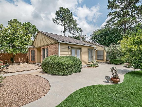 View of home from the Side Courtyard. French doors enter the Family space from the patio with a 2nd seating area to the right. Stone Patio between the garage and house.