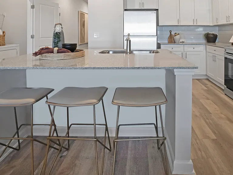 Kitchen island with bar seating. looking into the full kitchen with a view of the washer and dryer off to the left.