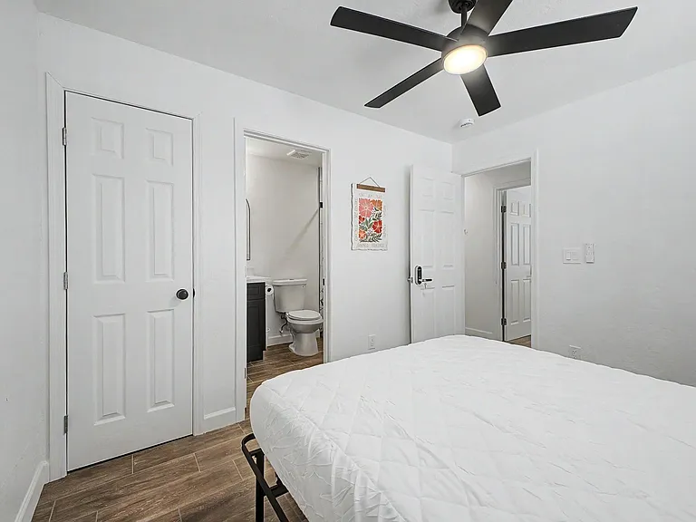 Private bedroom with ceiling fan, wood-look flooring, and convenient en-suite bath plus closet storage nearby.