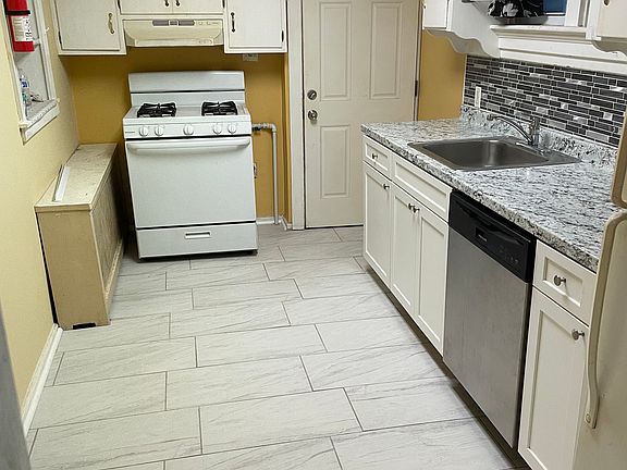 New tile flooring and tile backsplash in kitchen with a fresh paint job.