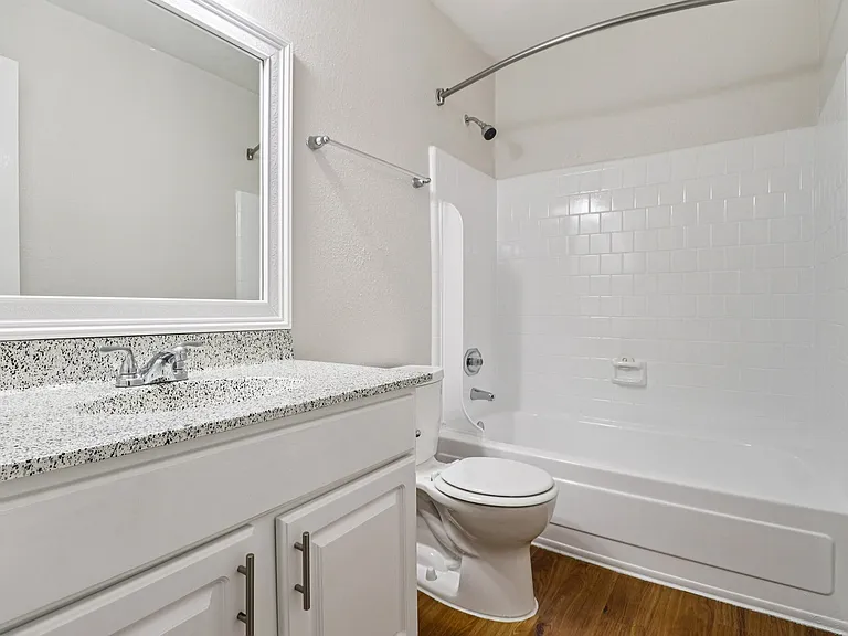Elegant bathroom with a modern speckled countertop, sleek white cabinetry, and a classic bathtub with tiled walls. Elegant bathroom with a modern speckled countertop, sleek white cabinetry, and a classic bathtub with tiled walls.
