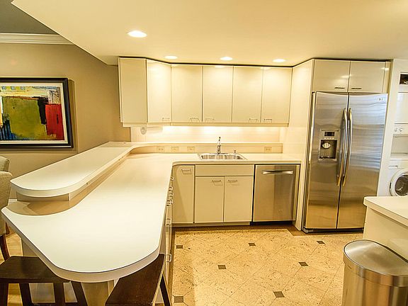 Kitchen with former countertops and cork floor which have been replaced with custom Cambria Quartz countertops and luxury vinyl plank floor.