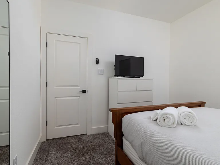 Second bedroom featuring a queen bed and tv.