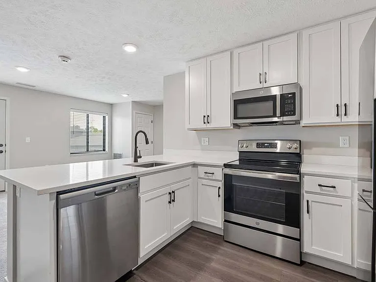 Bright white cabinetry, sleek stainless steel appliances, and an open layout create a kitchen that feels both fresh and effortlessly welcoming.