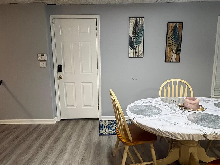 Dining area with a round table setup, durable plank-style flooring, and convenient access near the entry.