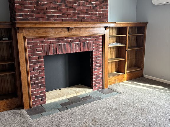 Living Room with brick fireplace and cozy wooden shelves on both sides. Fireplace is NOT active.