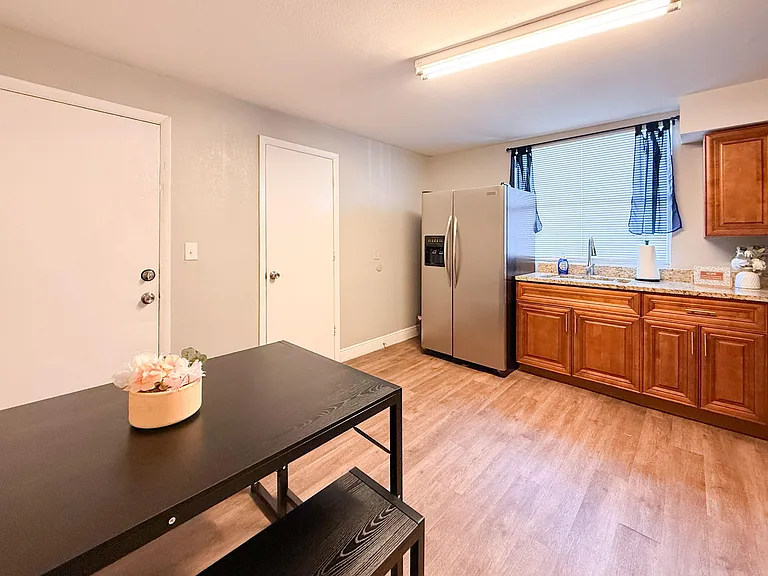 Kitchen with ample wood cabinetry, granite-look counters, stainless fridge, and a dining nook beside the sink window.