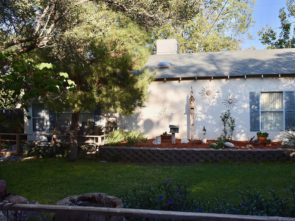 Beautiful landscaping in yard facing front of home. Gated deck area with seating.