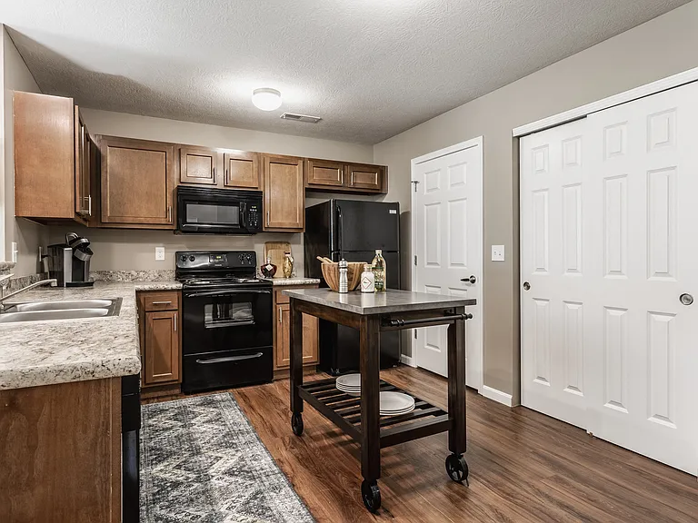 Experience a beautifully designed kitchen with a central island, sleek black appliances, granite countertops, and warm wooden cabinetryperfect for cooking and entertaining.