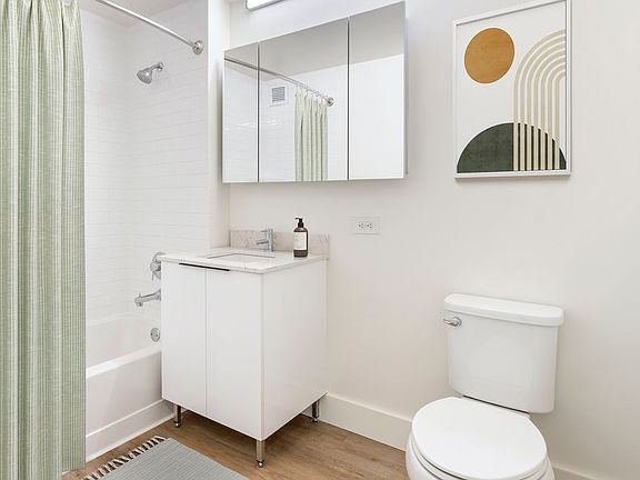 Renovated Package I bath with white marbled quartz countertops, white cabinetry, and hard surface flooring