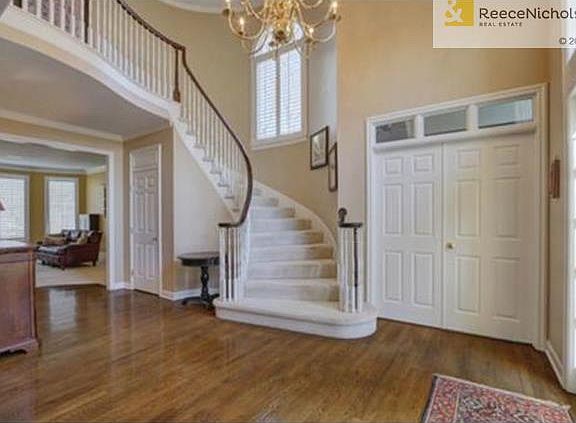 Entry features elegant curved staircase and french doors leading