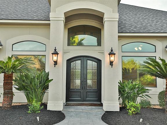 DOUBLE IRON CANTERRA DOORS - The stunning entrance makes a beautiful statement, featuring dual carriage lights and arched Canterra doors. The window above the door allows a lot of natural light through to the foyer.