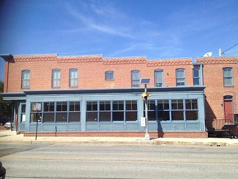 Full length of 2nd floor apartment with red entrance door at the rear.