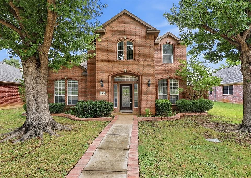 Brick facade with arched entry, complementing arched windows, and mature trees framing the property