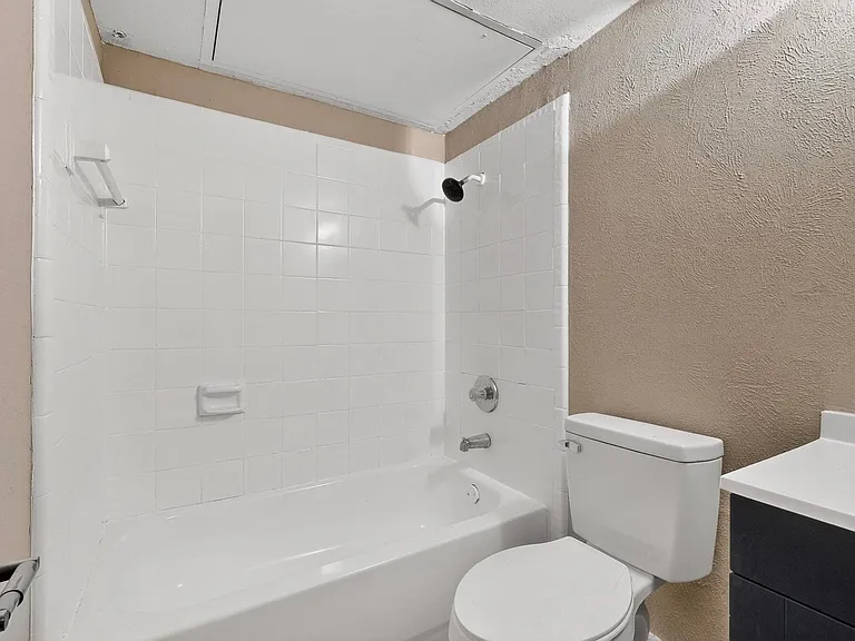 Bathroom featuring a textured wall, vanity, and bathing tub / shower combination