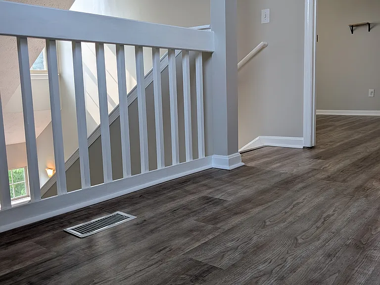 Upper-level landing featuring open banister railings, updated luxury vinyl plank flooring, and seamless access to bedrooms